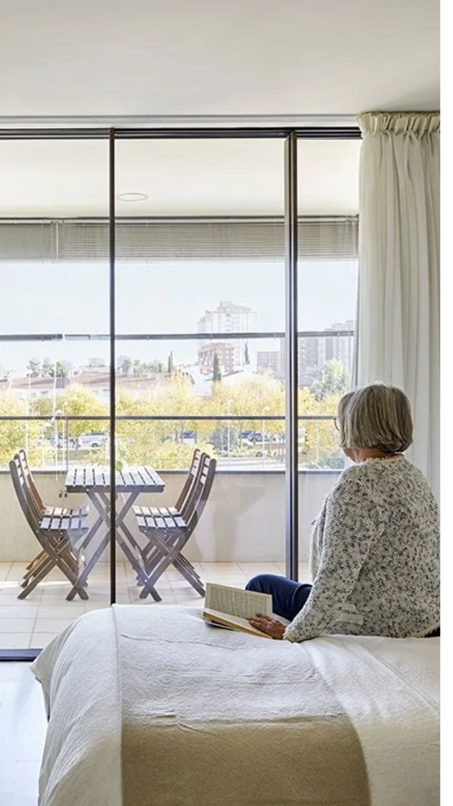 Dormitorio con ventanal y mujer leyendo